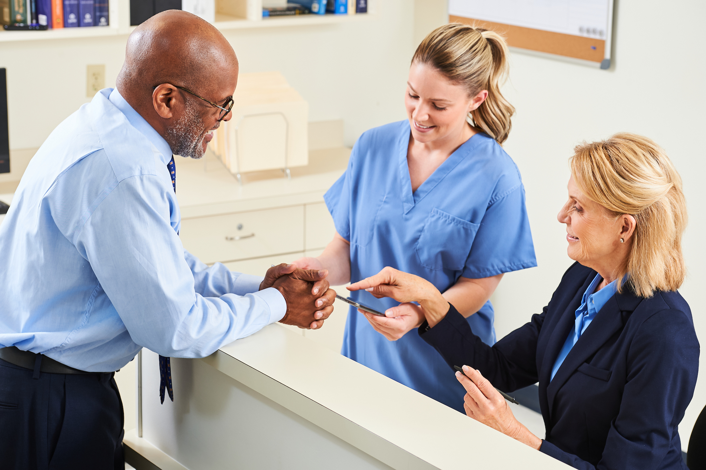 Healthcare administrators talking with a nurse at her station.